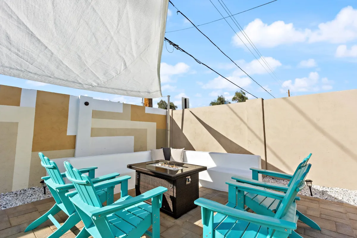 A cozy fire pit area with stylish turquoise chairs arranged in a circle, set against a textured wall. This inviting scene is perfect for evening conversations, roasting marshmallows, or simply unwinding by the warmth of the fire under the stars.