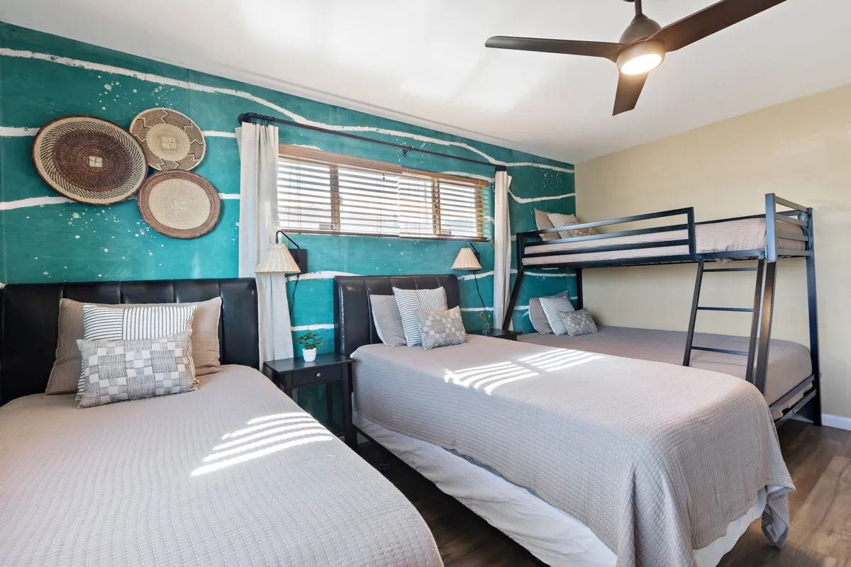 A cozy and playful kids' bedroom with a colorful accent wall, a bunk bed, comfortable bedding, and decorative wall plates. The room exudes warmth and is clearly designed with children in mind, making it ideal for sleepovers, play, and family bonding.