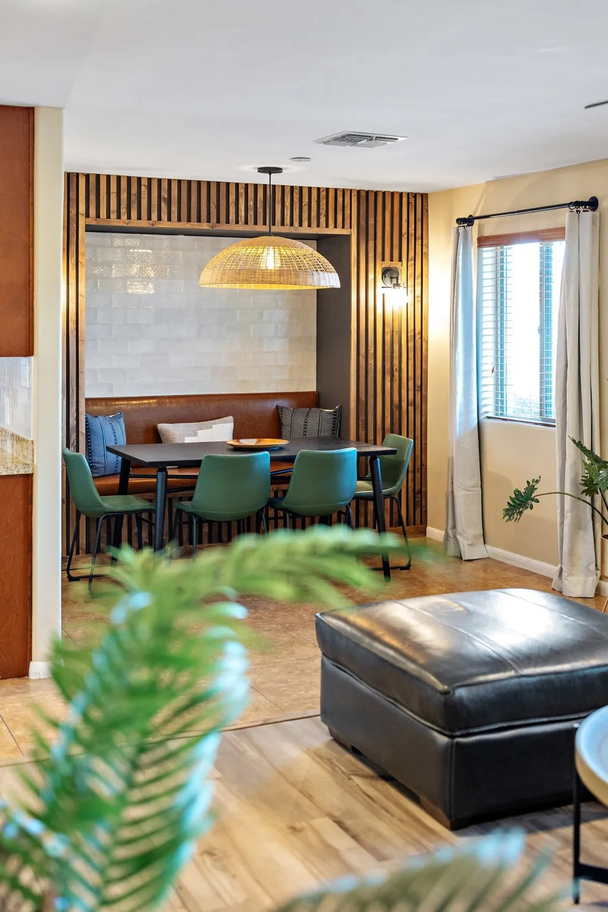 A welcoming dining space with a large table surrounded by green chairs, a statement light fixture overhead, and a warm, cozy atmosphere. The setting is perfect for family meals, celebrations, and connecting over food.