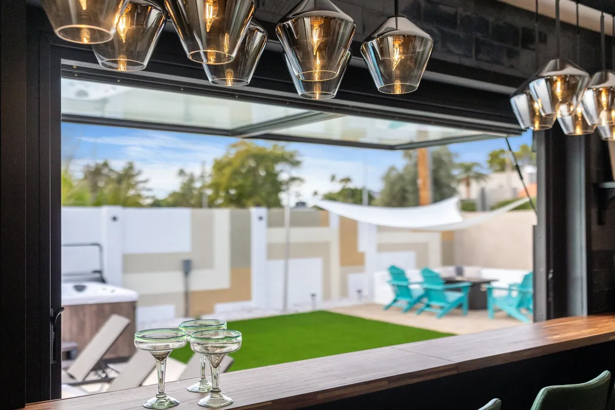 A view of an indoor-outdoor transition area, featuring stylish hanging lights, glassware, and a glimpse of an outdoor space beyond. This scene suggests easy access from the interior to the outdoors—perfect for coming and going with a pet.
